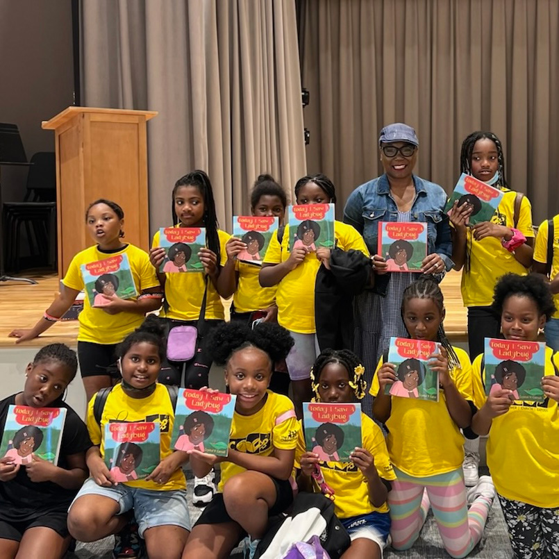 Girls from Camp Honey Shine pose for a photo with Crystal V. Carrollwho shared her whimsical book "Today I Saw A Ladybug"..