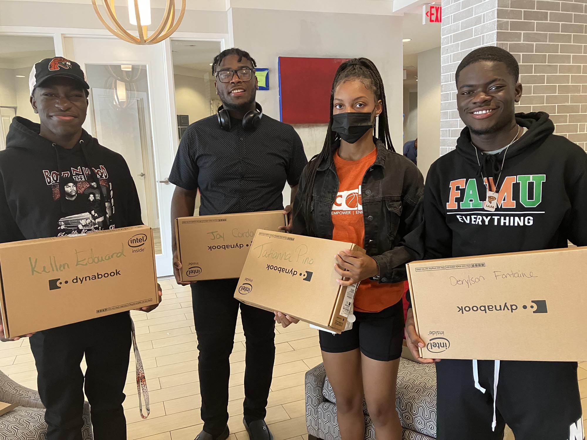 A group of seniors holds up their new laptops provided by Overtown Children & Youth Coalition
