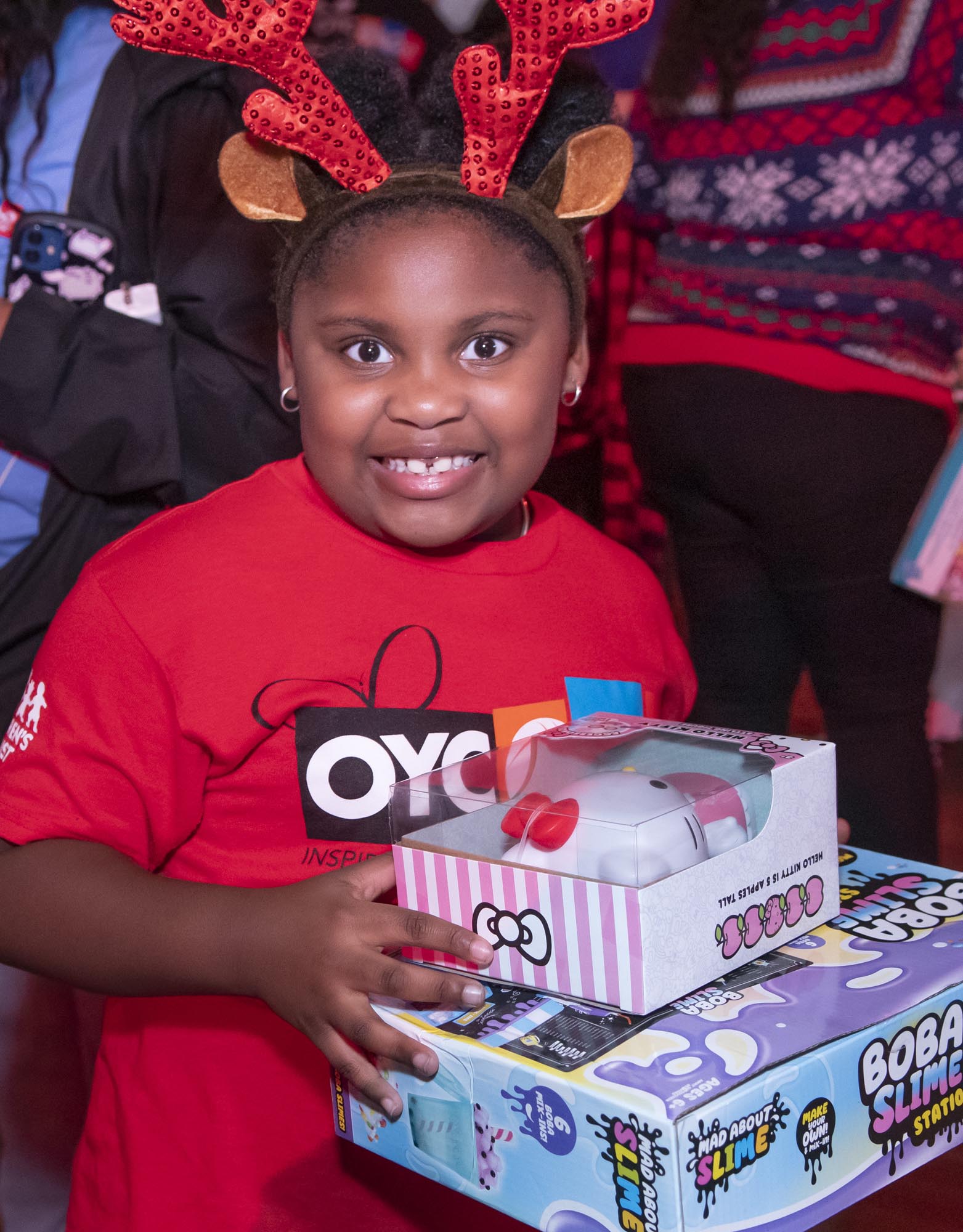 A child with her gifts poses for a photo at the Mourning Family Foundation holiday party.